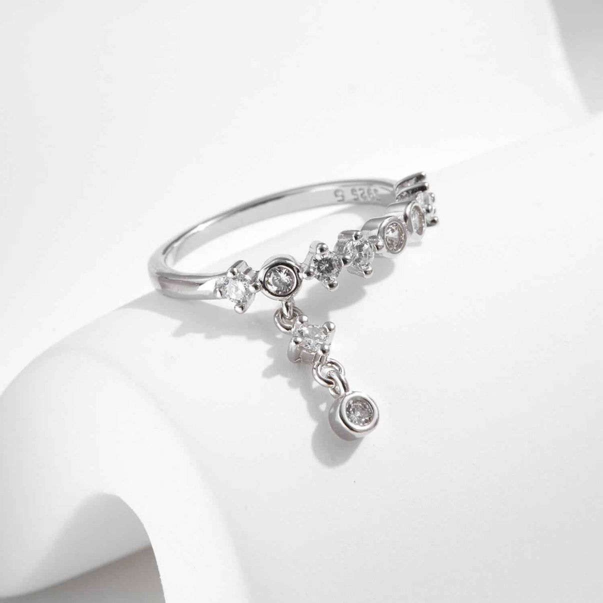 kinetic floating tassel drop ring in platinum plated s925 sterling silver with half loop bezel prong eternity band and hanging clear cz charm