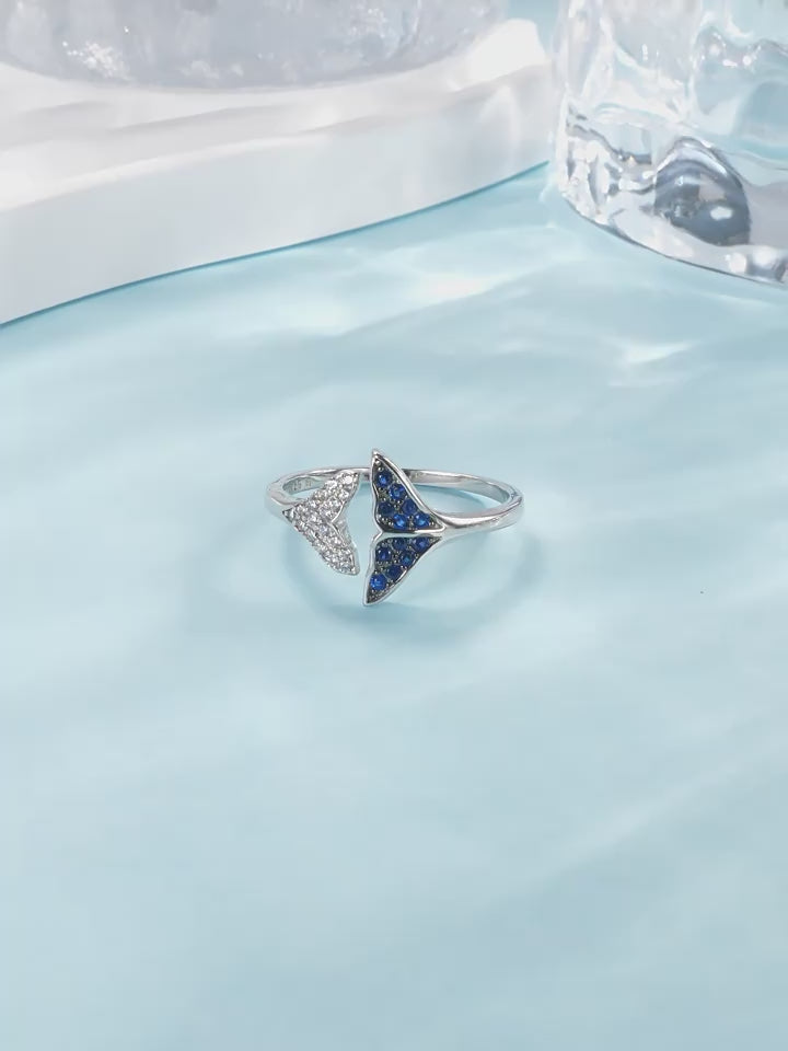 Asymmetric whale tail open-ended ring with blue and white zircon pavé in rhodium-plated 925 silver, artfully engineered for a snag-free fit.