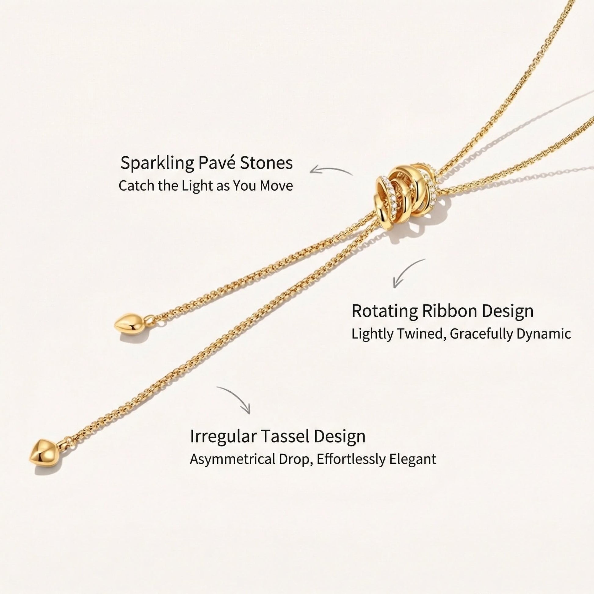 Close-up of a gold lariat necklace featuring sparkling pavé stones, rotating ribbon design, and irregular tassel drops with descriptions.